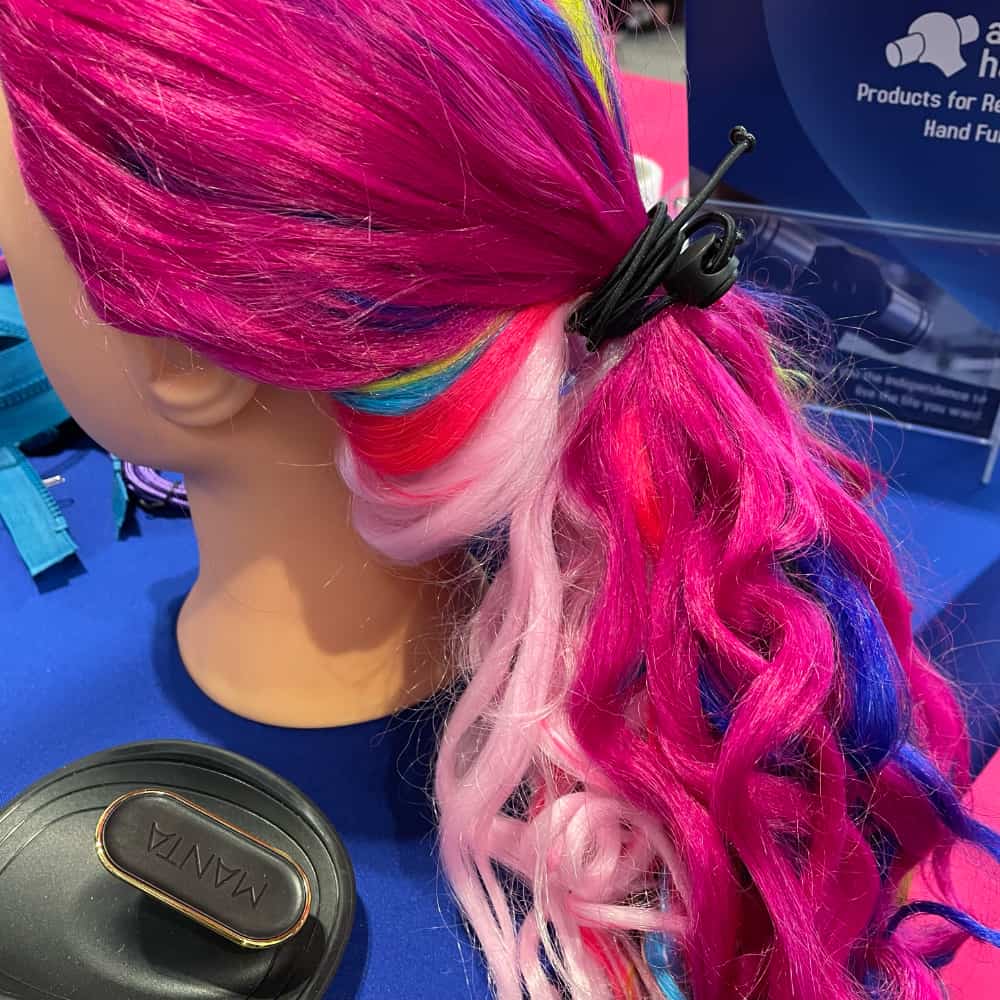 Das einhändige Haarband im regenbogenfarbenen Haar eines Friseurausbildungskopfes